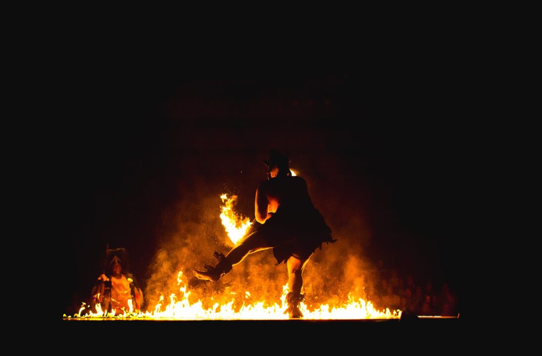 Man danst in het donker voor een vuur