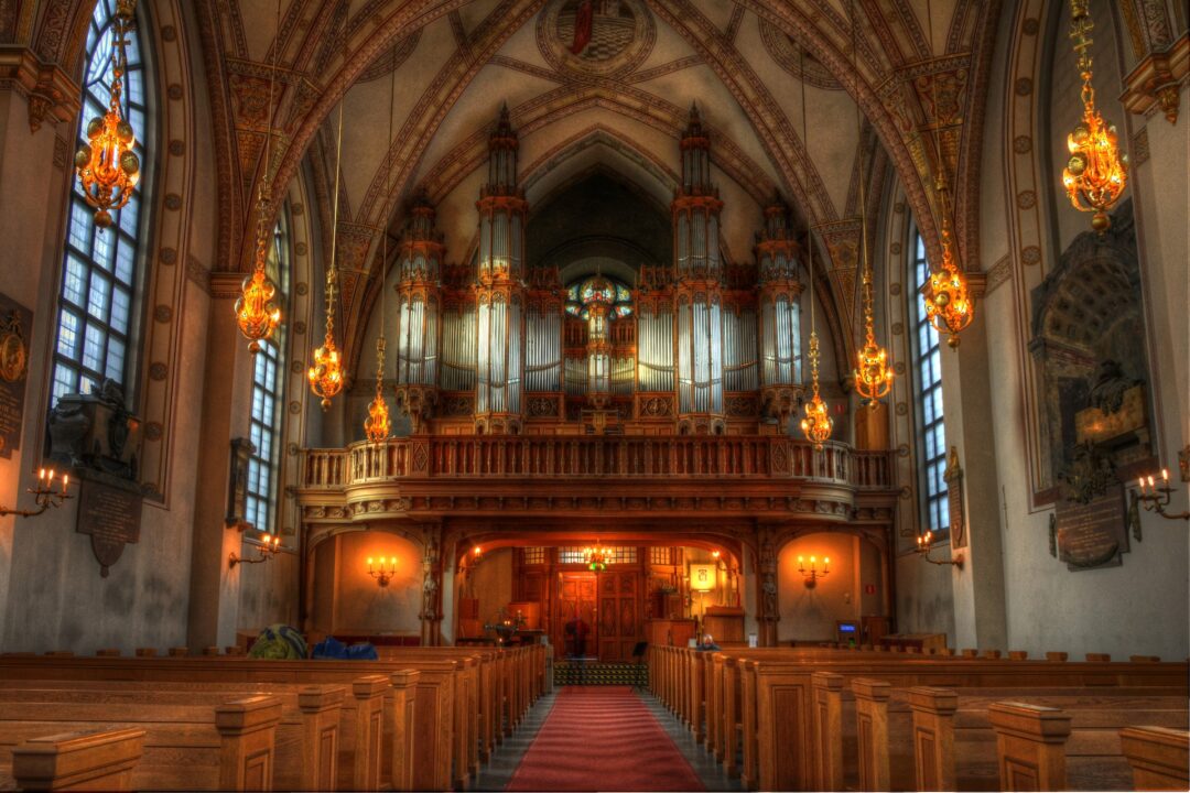 Interieur van een kerk, lege kerkbanken, hoge bogen, groot orgel,zacht licht.