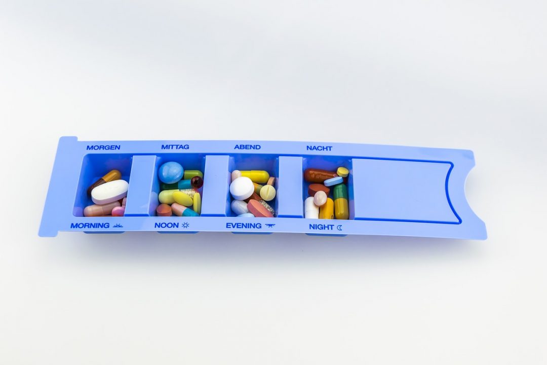Een blauw pillendoosje met verschillende soorten pillen erin
